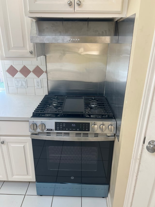 kitchen featuring tasteful backsplash, stainless steel range with gas stovetop, exhaust hood, and white cabinets