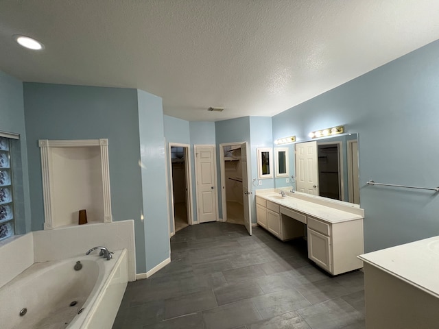 bathroom with vanity, a tub, and a textured ceiling