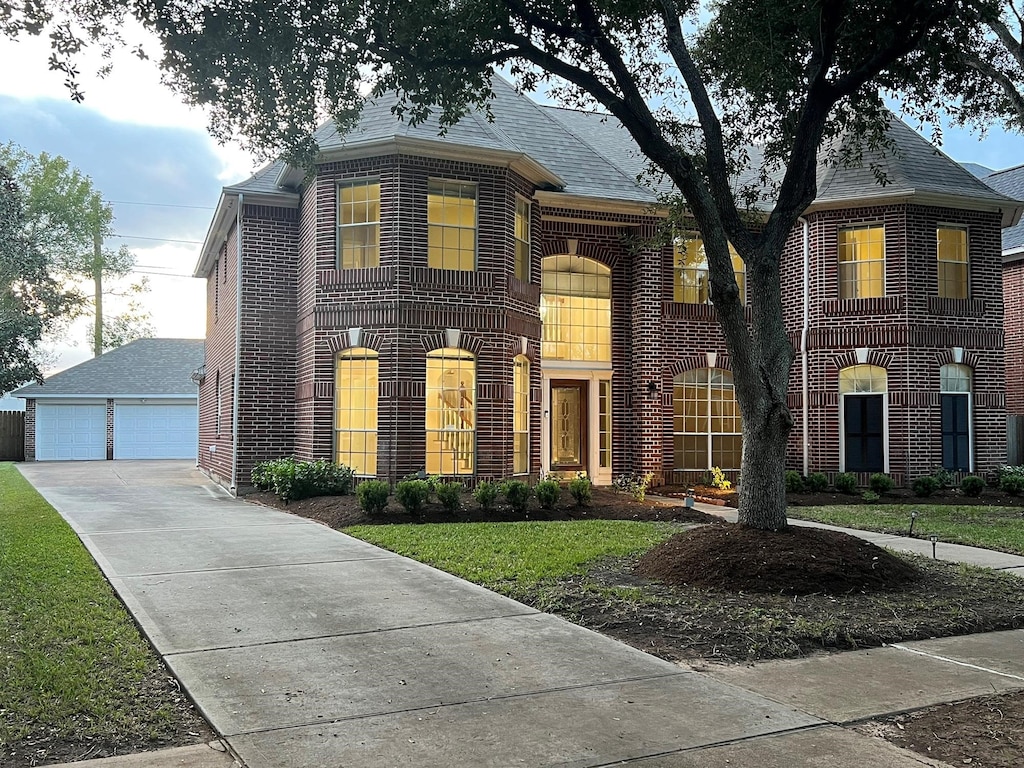 view of front facade featuring a garage, an outdoor structure, and a front lawn