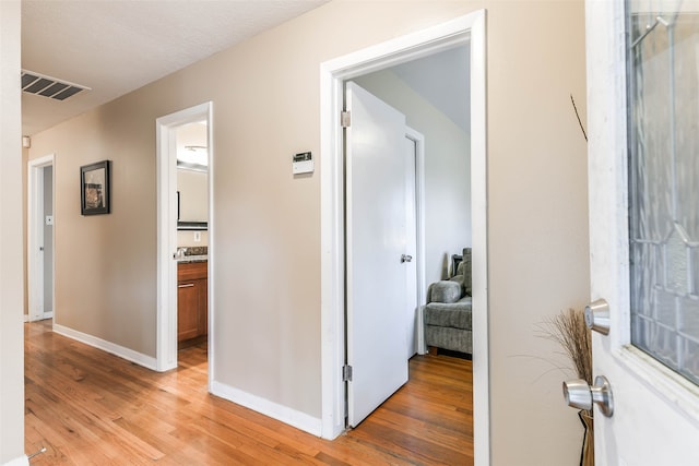 corridor with a textured ceiling and light wood-type flooring