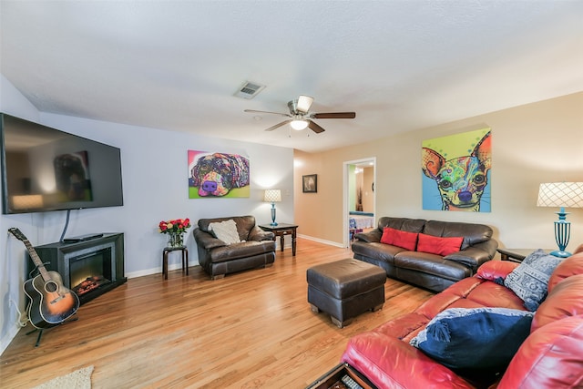 living room featuring ceiling fan, hardwood / wood-style flooring, and a fireplace