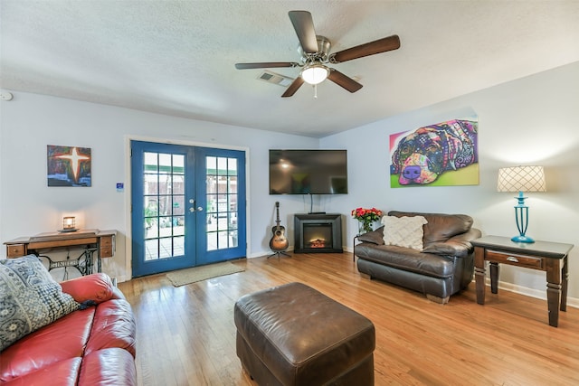 living room with french doors, light hardwood / wood-style floors, a textured ceiling, and ceiling fan