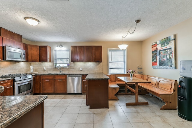 kitchen featuring a healthy amount of sunlight, stainless steel appliances, sink, and pendant lighting