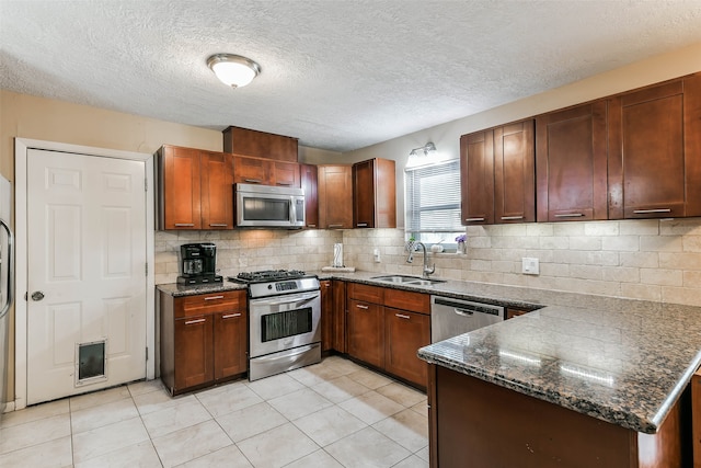 kitchen featuring dark stone countertops, sink, light tile patterned floors, appliances with stainless steel finishes, and tasteful backsplash