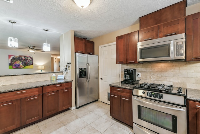 kitchen with appliances with stainless steel finishes, backsplash, decorative light fixtures, dark stone countertops, and light tile patterned floors