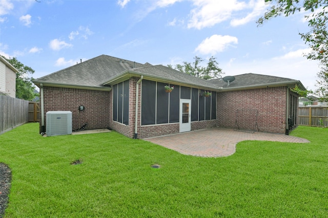 rear view of property with a sunroom, a patio, a lawn, and central AC