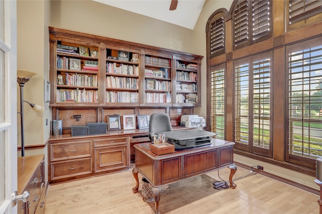 home office with high vaulted ceiling, plenty of natural light, and light hardwood / wood-style flooring