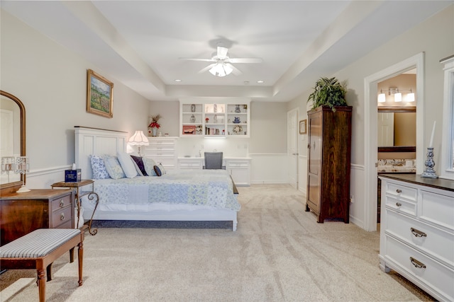 carpeted bedroom featuring ensuite bathroom, ceiling fan, and a raised ceiling