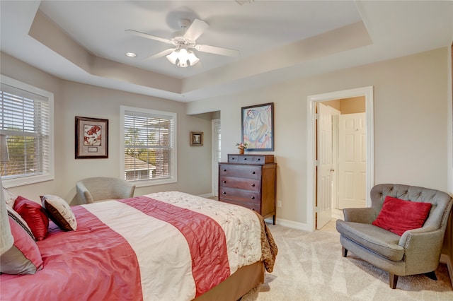 bedroom featuring light colored carpet, ceiling fan, and a tray ceiling