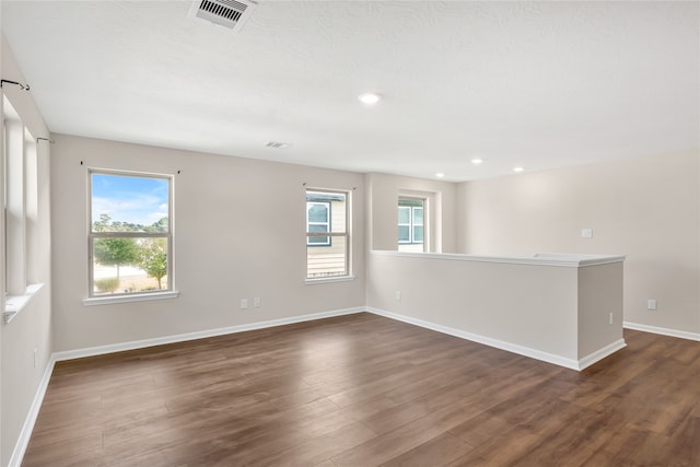 empty room featuring a wealth of natural light and dark wood-type flooring