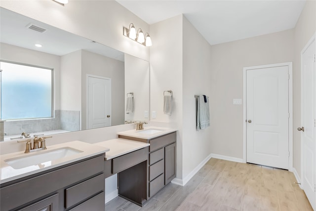 bathroom with vanity, wood-type flooring, and a tub