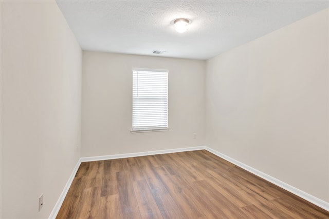 empty room with hardwood / wood-style flooring and a textured ceiling