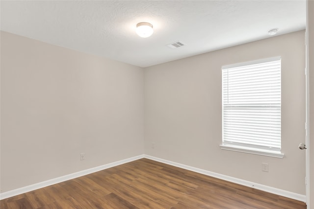 spare room with dark wood-type flooring and a textured ceiling