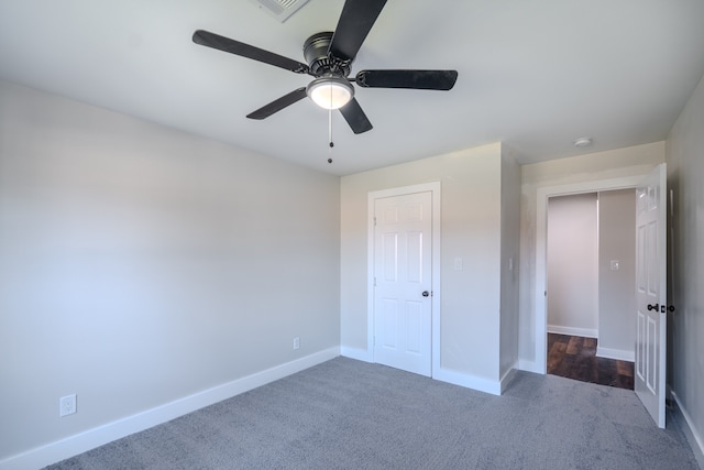 unfurnished bedroom with ceiling fan, dark carpet, and a closet