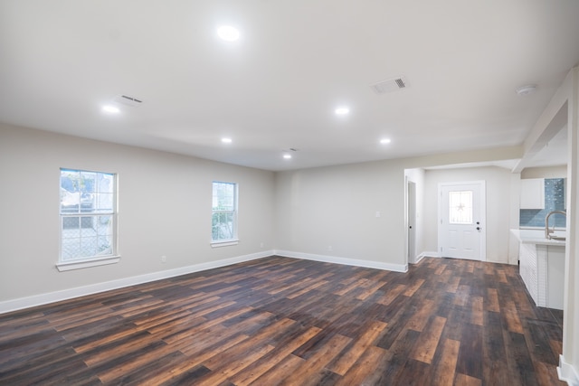 unfurnished living room with a wealth of natural light, sink, and dark wood-type flooring