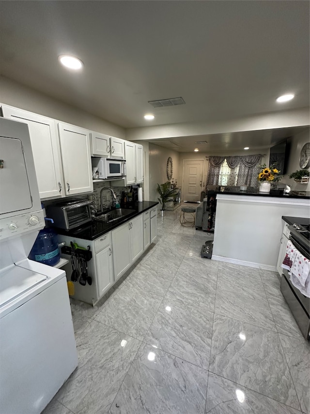 kitchen featuring white cabinetry, stacked washer and dryer, sink, and black / electric stove