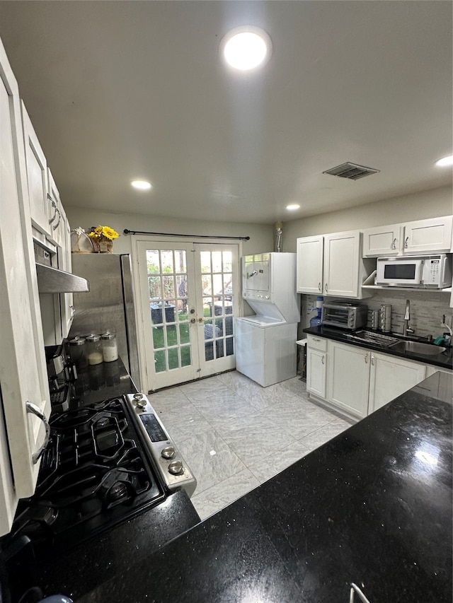 kitchen with decorative backsplash, white cabinets, black gas range, french doors, and sink