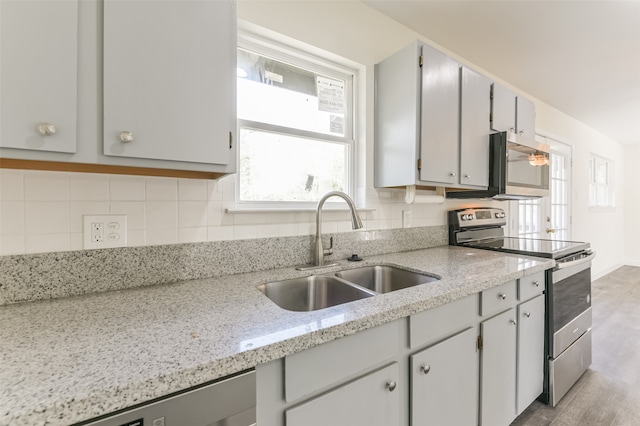 kitchen with light stone counters, stainless steel appliances, tasteful backsplash, and sink