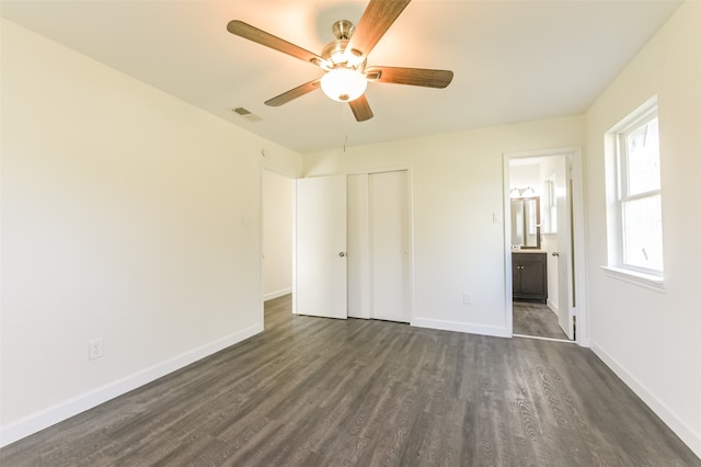 unfurnished bedroom with a closet, ensuite bathroom, dark hardwood / wood-style flooring, and ceiling fan