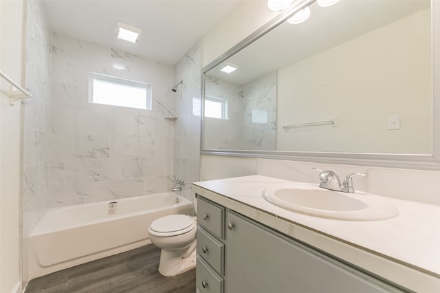 full bathroom with tiled shower / bath, vanity, hardwood / wood-style floors, and toilet