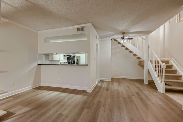 unfurnished living room with ceiling fan, a textured ceiling, and light wood-type flooring