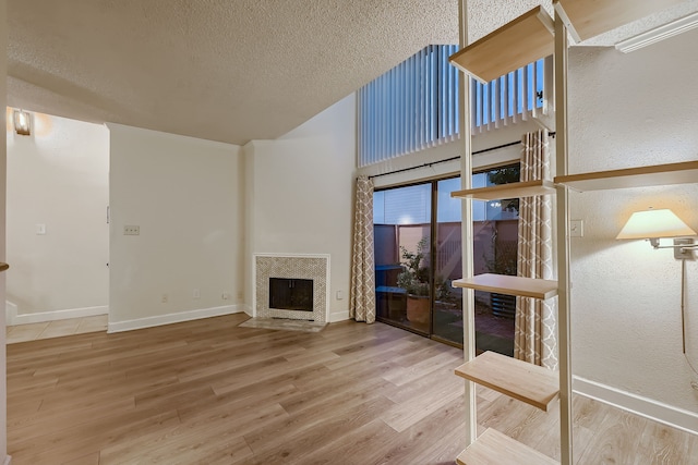 unfurnished living room featuring hardwood / wood-style floors, a fireplace, and a textured ceiling