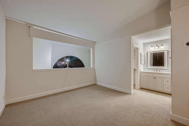 unfurnished bedroom with light colored carpet, connected bathroom, and sink