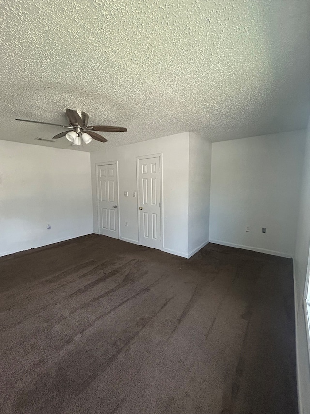 unfurnished room featuring a textured ceiling, dark carpet, and ceiling fan