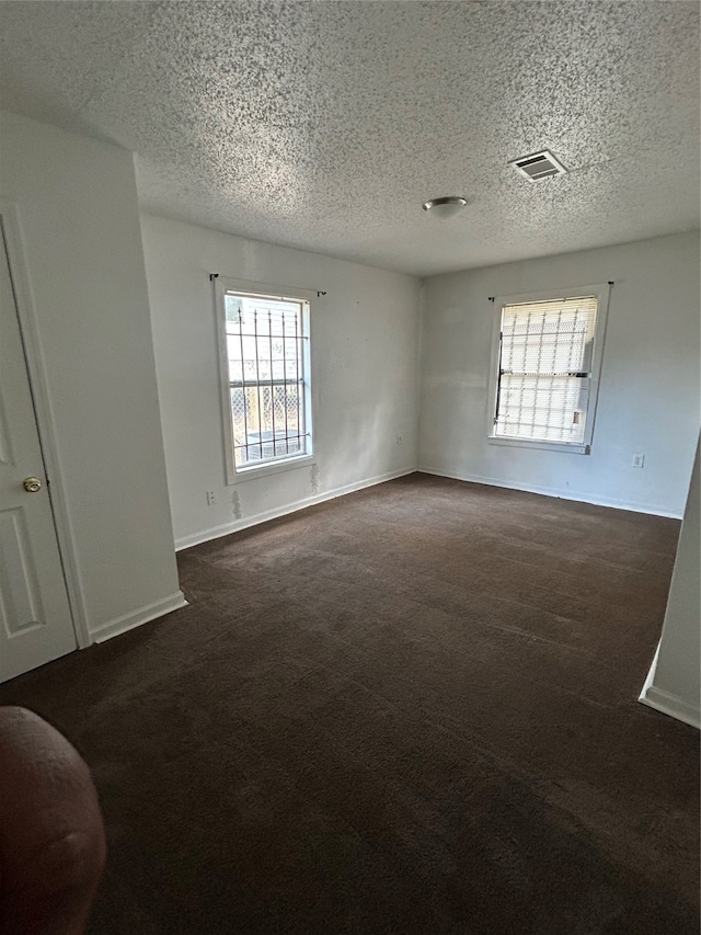 spare room with dark colored carpet and a textured ceiling