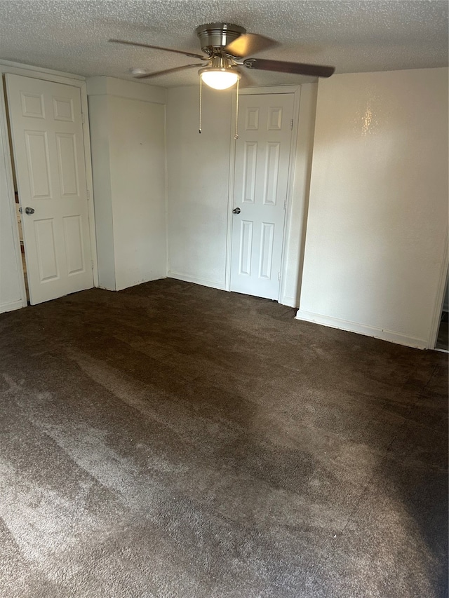 unfurnished room with a textured ceiling, dark carpet, and ceiling fan