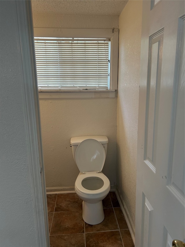 bathroom with toilet, a textured ceiling, and tile patterned flooring