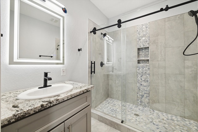 bathroom with a shower with door and vanity