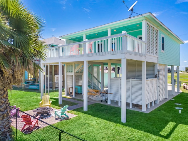 back of property featuring a yard, an outdoor fire pit, a deck, and a patio