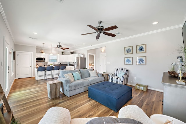 living room with light hardwood / wood-style floors, crown molding, and ceiling fan