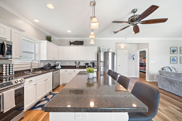 kitchen with appliances with stainless steel finishes, sink, light wood-type flooring, a center island, and white cabinets