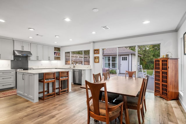 dining space with light hardwood / wood-style flooring, ornamental molding, and sink