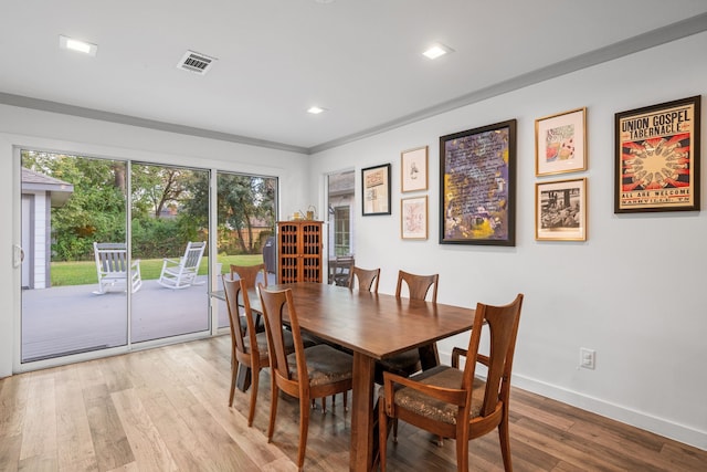 dining area with crown molding and light hardwood / wood-style flooring