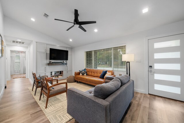 living room featuring ceiling fan, vaulted ceiling, and light wood-type flooring