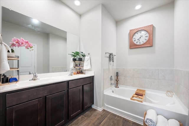 bathroom featuring hardwood / wood-style flooring, a tub to relax in, and vanity