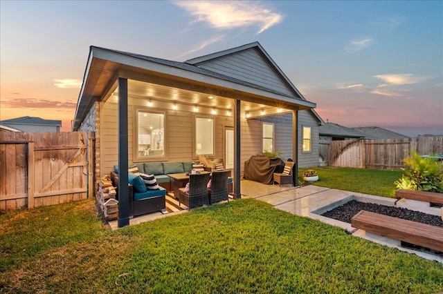 back house at dusk with a patio area, a yard, and an outdoor hangout area