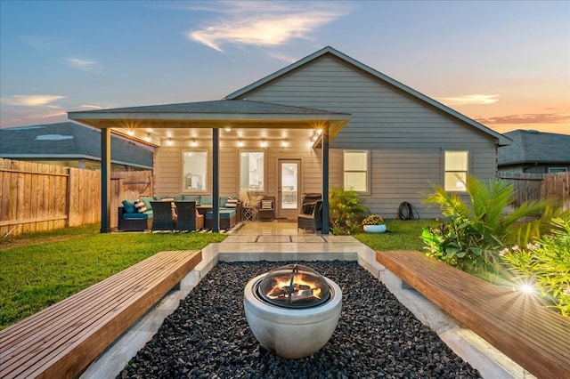 back house at dusk with an outdoor living space with a fire pit and a patio area