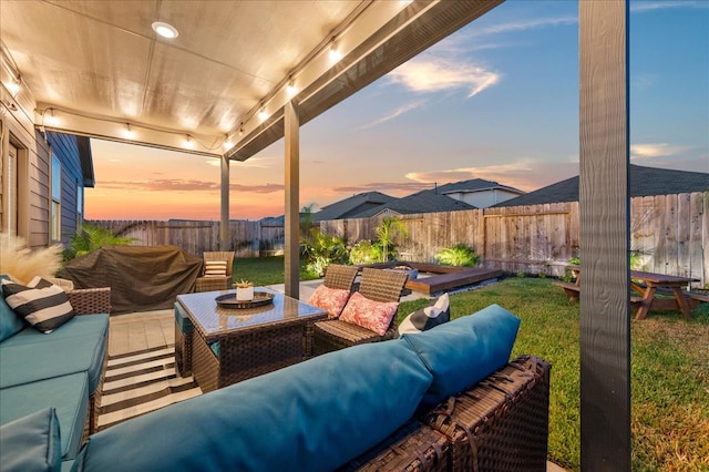 patio terrace at dusk with an outdoor living space with a fire pit and a yard