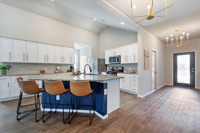 kitchen with stainless steel appliances, a center island with sink, white cabinetry, hanging light fixtures, and dark wood-type flooring