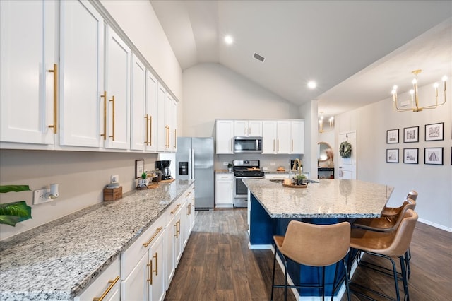 kitchen with stainless steel appliances, a center island, vaulted ceiling, dark hardwood / wood-style floors, and white cabinetry