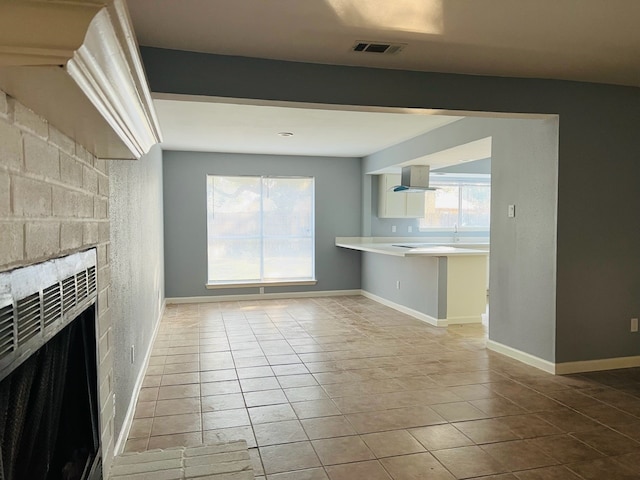 unfurnished living room with light tile patterned floors and a wealth of natural light