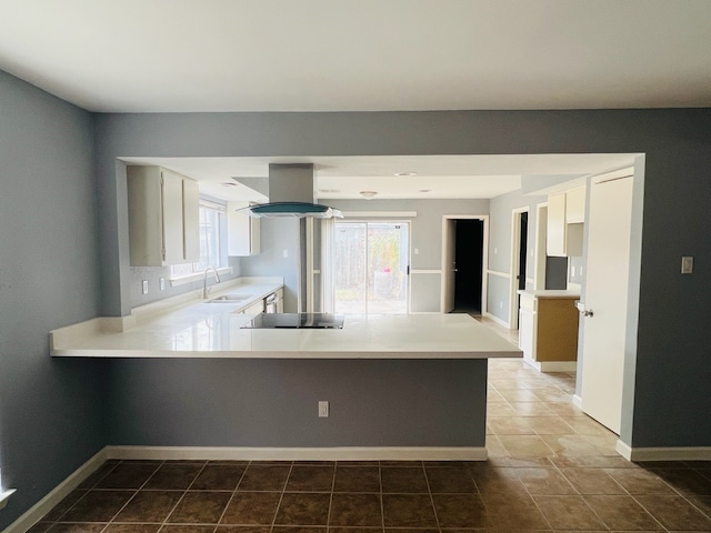 kitchen with island exhaust hood, black stovetop, kitchen peninsula, sink, and white cabinetry