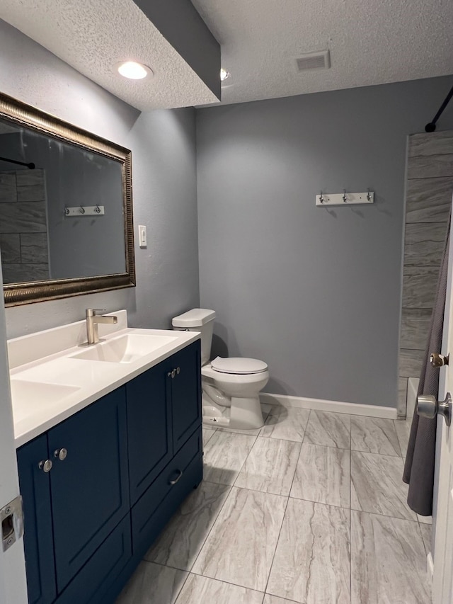 bathroom with vanity, a textured ceiling, walk in shower, and toilet