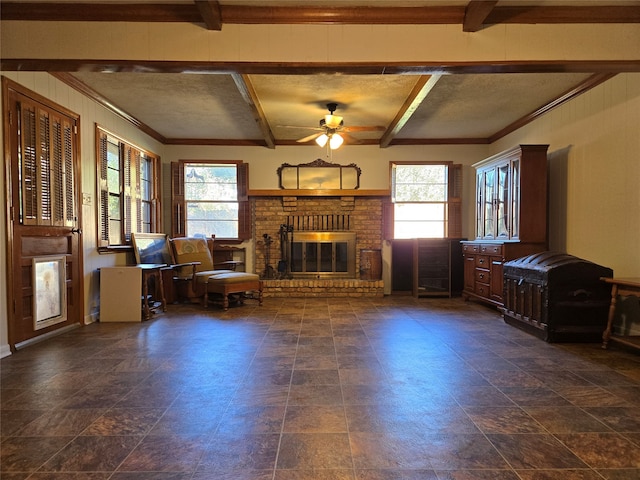 unfurnished living room with a brick fireplace, a textured ceiling, beamed ceiling, and ceiling fan