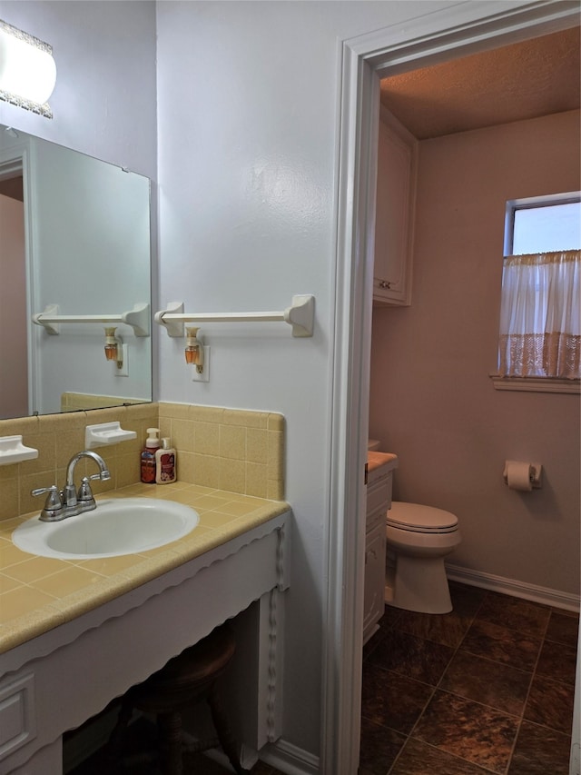 bathroom featuring vanity, toilet, and backsplash