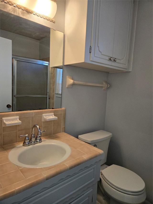 bathroom with backsplash, vanity, toilet, and an enclosed shower